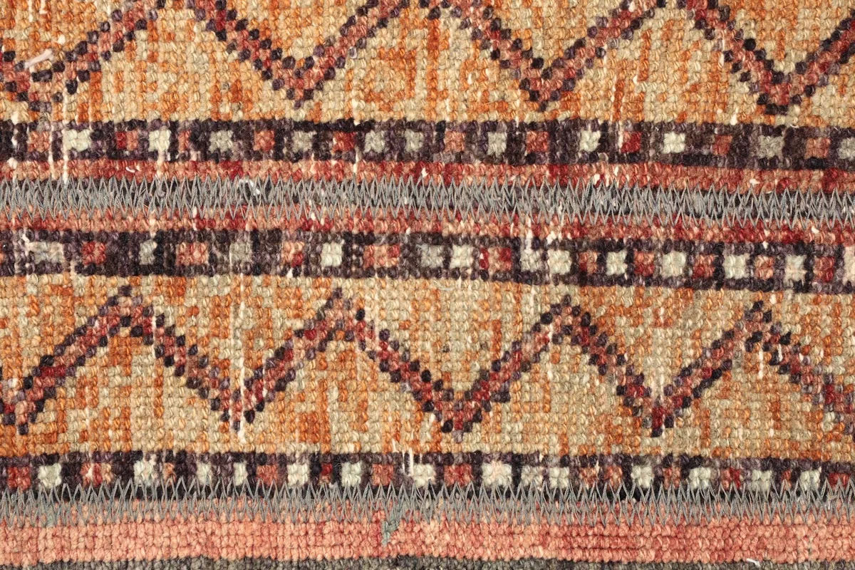 Detailed close-up of the central orange field with zigzag and striped tribal patterns in red and gray.