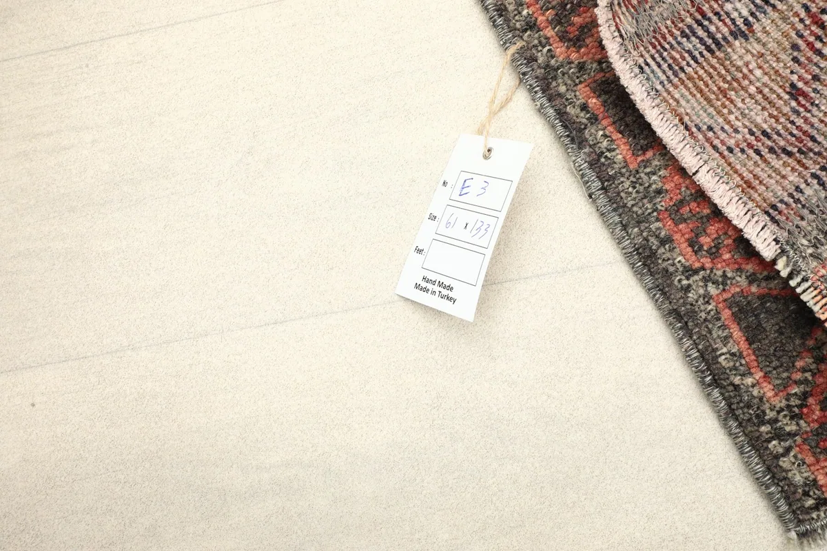 Close-up of the rug's back and a product tag, illustrating the hand-knotted craftsmanship.