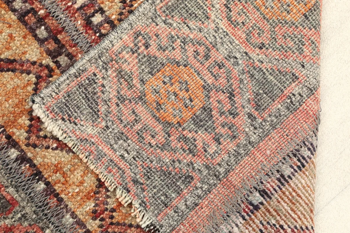 Corner of the rug folded back, showing the wool pile and cotton foundation construction.