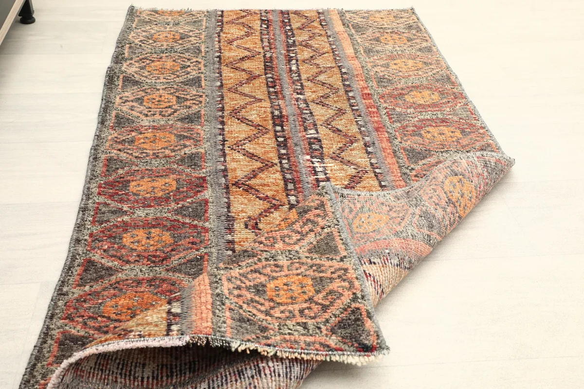 Rug partially folded, revealing the back of the hand-knotted wool and cotton construction.