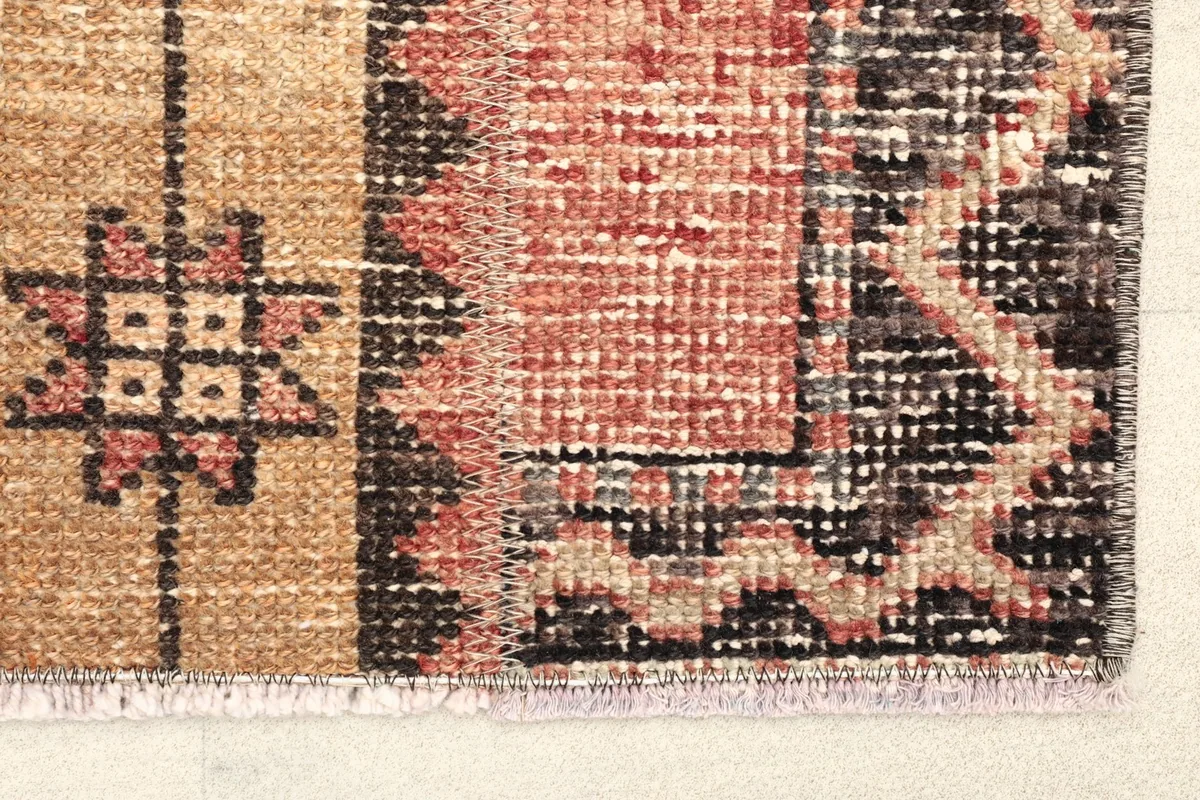 Close-up detail of the rust field, beige stripe, and black geometric border patterns.
