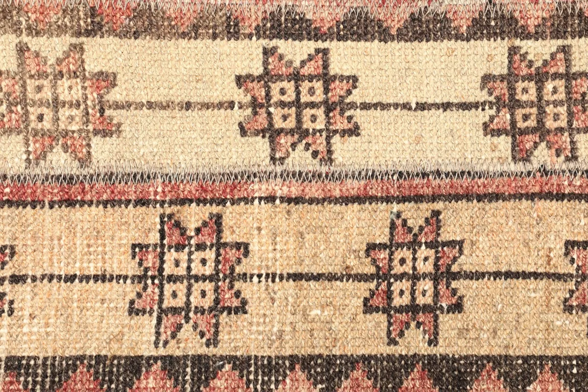 Detailed view of the beige stripes with repeating rust and black tribal motifs.