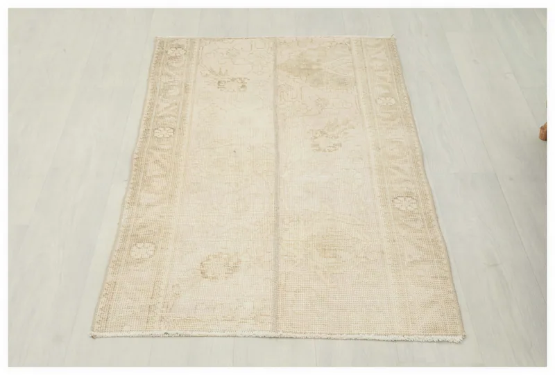 Full overhead view of the 2x4 ivory and beige vintage Anatolian rug on a white floor.