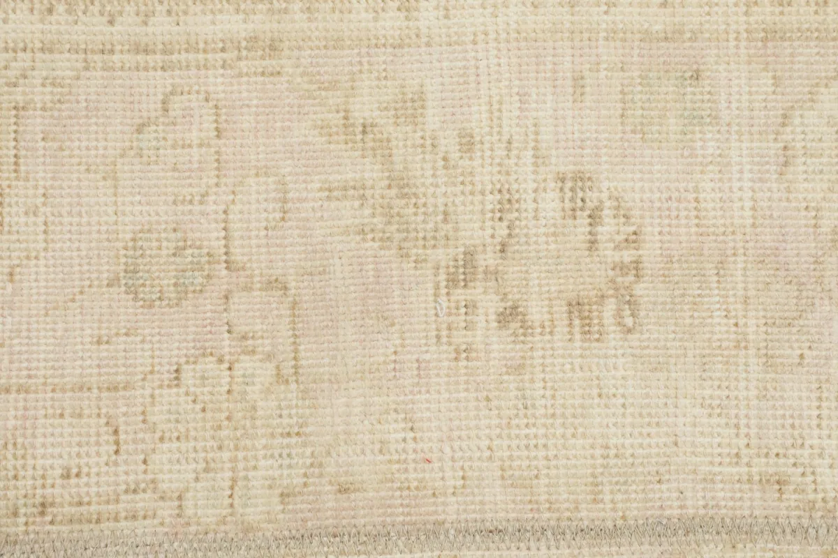 Extreme close-up of the rug's low pile, revealing the hand-knotted texture and faded wool.