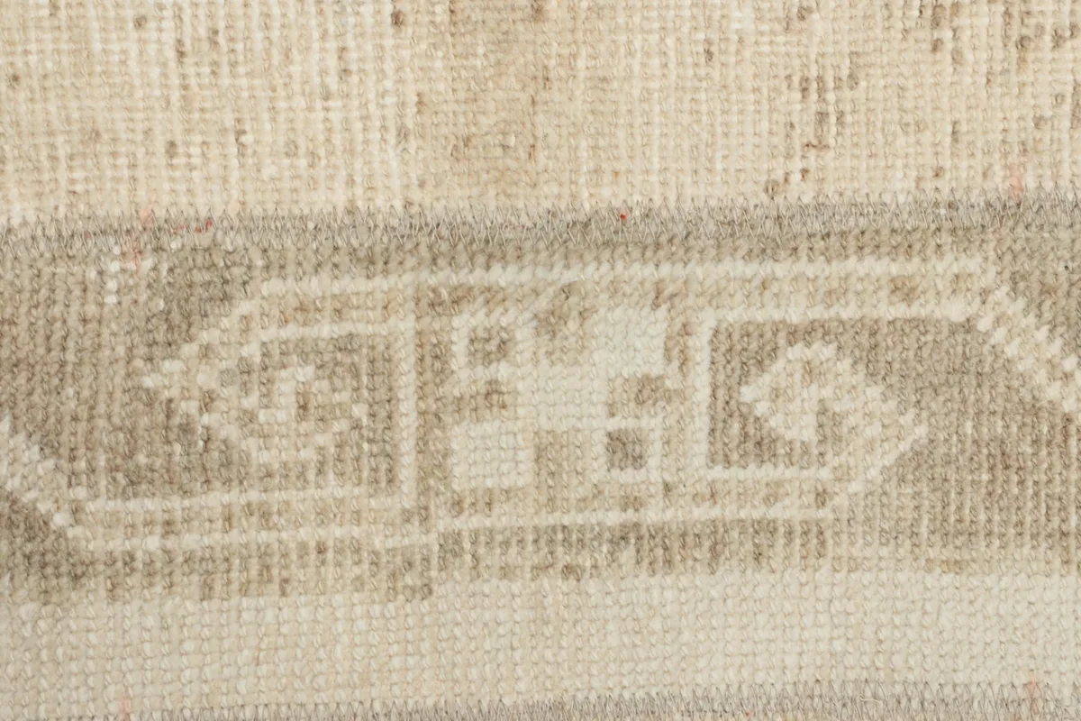 Extreme close-up of a specific tribal motif within the beige and cream rug
