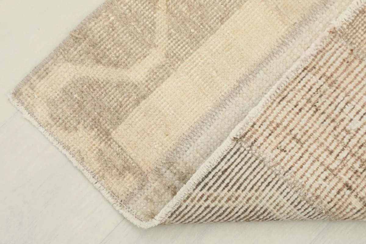 Corner of the rug folded back, revealing the woven cotton foundation