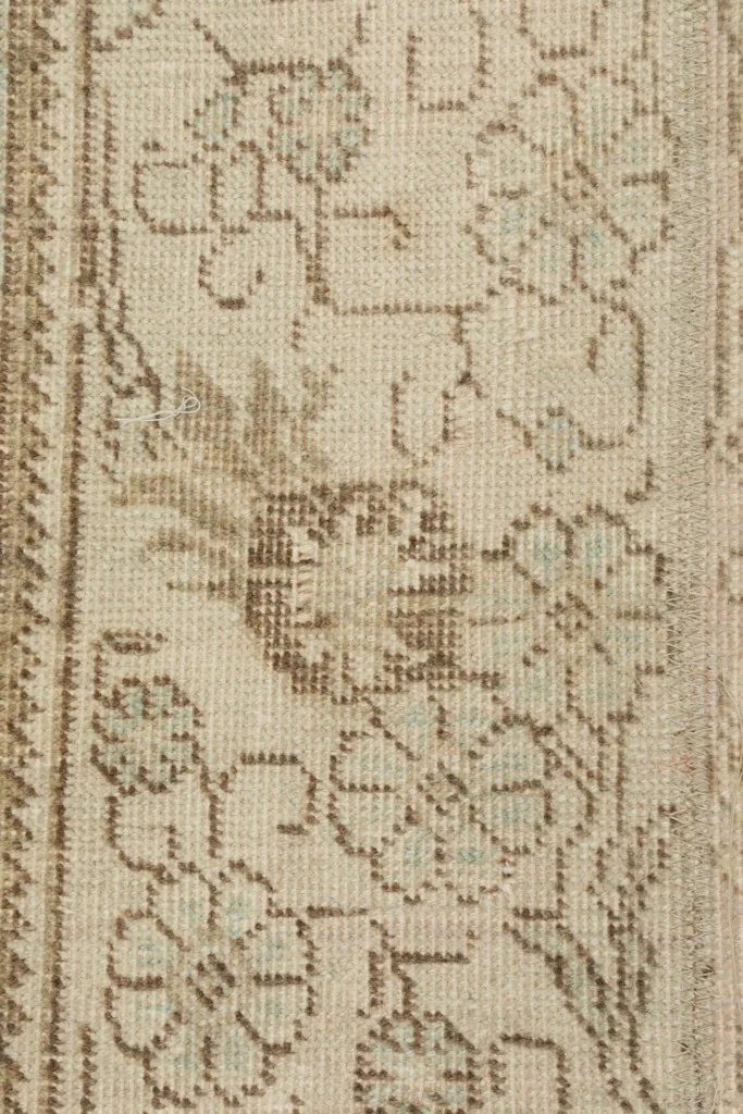 Extreme close-up of the low wool pile, revealing the hand-knotted texture and faded colors.