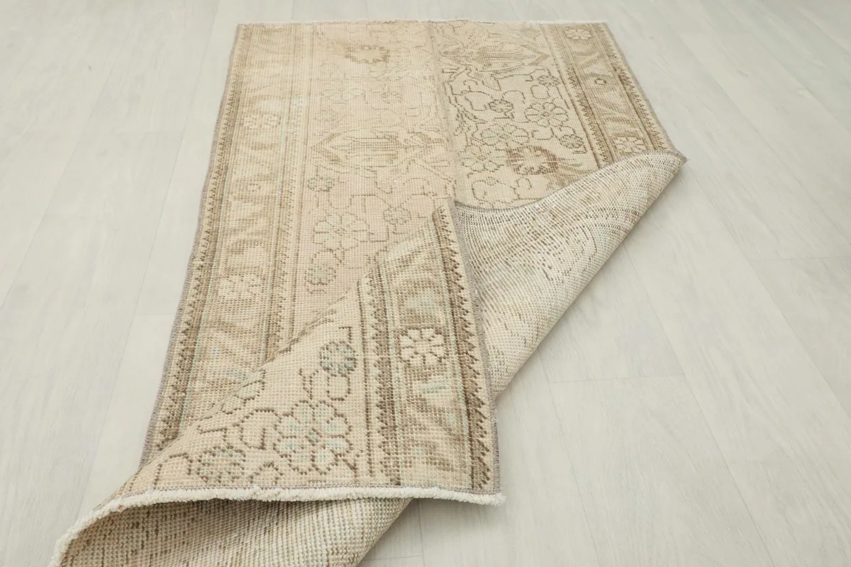Angled view of the rug with one corner folded back, displaying both the pile and the foundation.