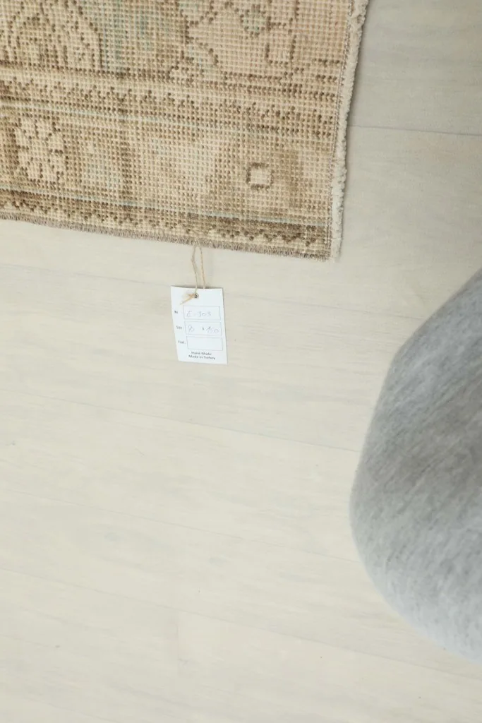 Overhead view showing the rug's corner with a product tag attached, on a light floor.