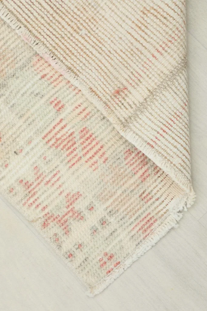 Corner of the rug folded to show the hand-knotted cotton foundation