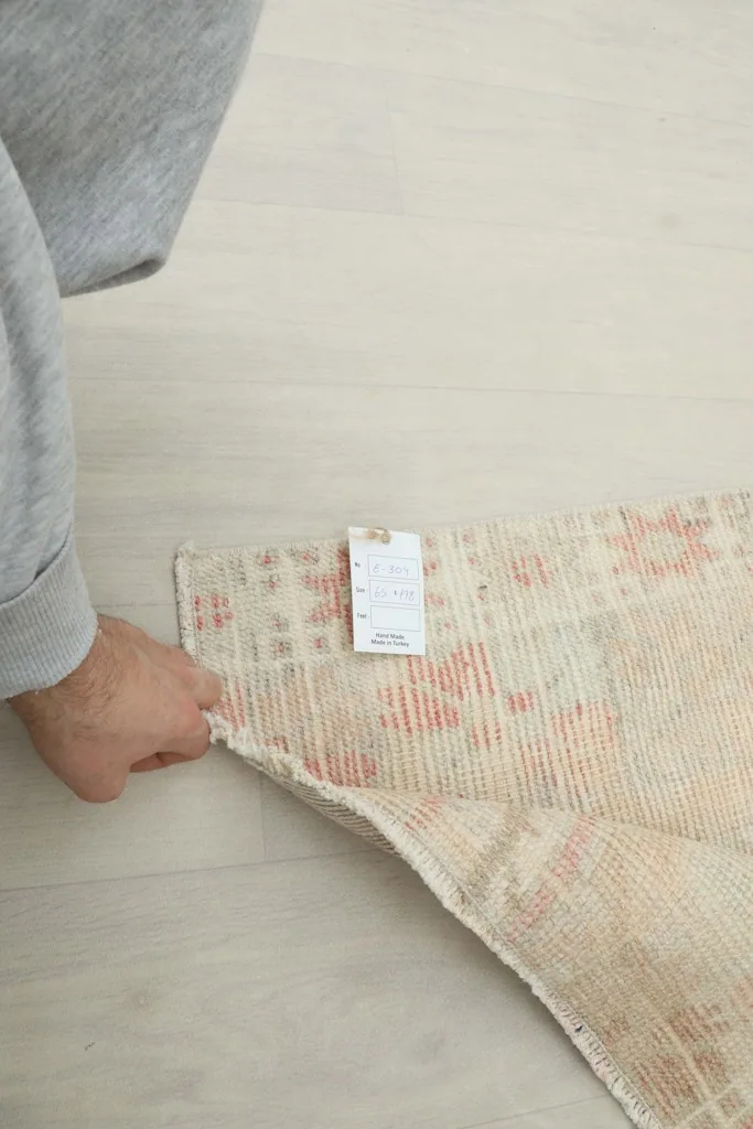 Hand holding the rug to display its flexibility and the attached product label