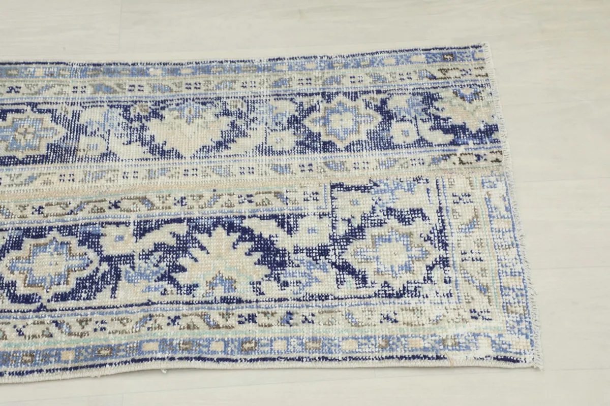 Close-up detail of one end of the blue and ivory rug, highlighting the geometric patterns and colors.