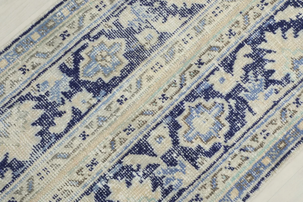 Diagonal close-up view of the rug's surface, showing the blend of blue, ivory, and gray yarns.