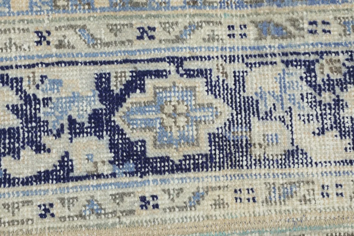 Extreme close-up of the low pile and hand-knotted wool texture of the vintage rug.