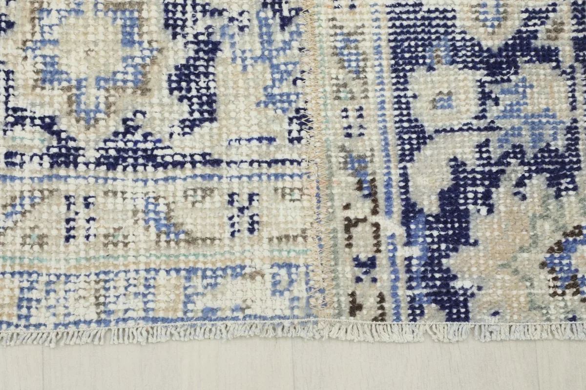 Detail of the short, aged fringe and the edge of the vintage hand-knotted rug.