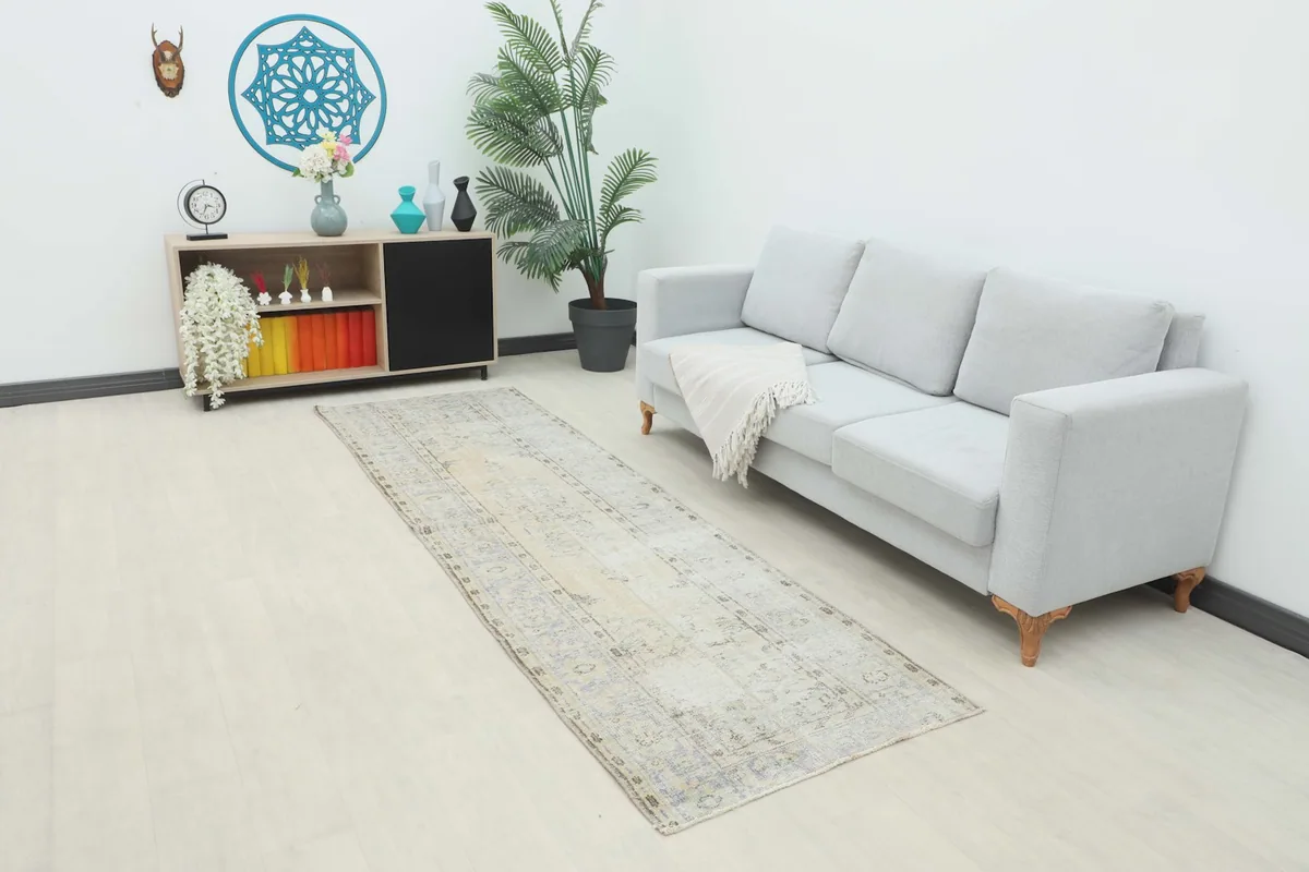 Runner rug placed in a living room setting next to a light gray sofa and modern console.