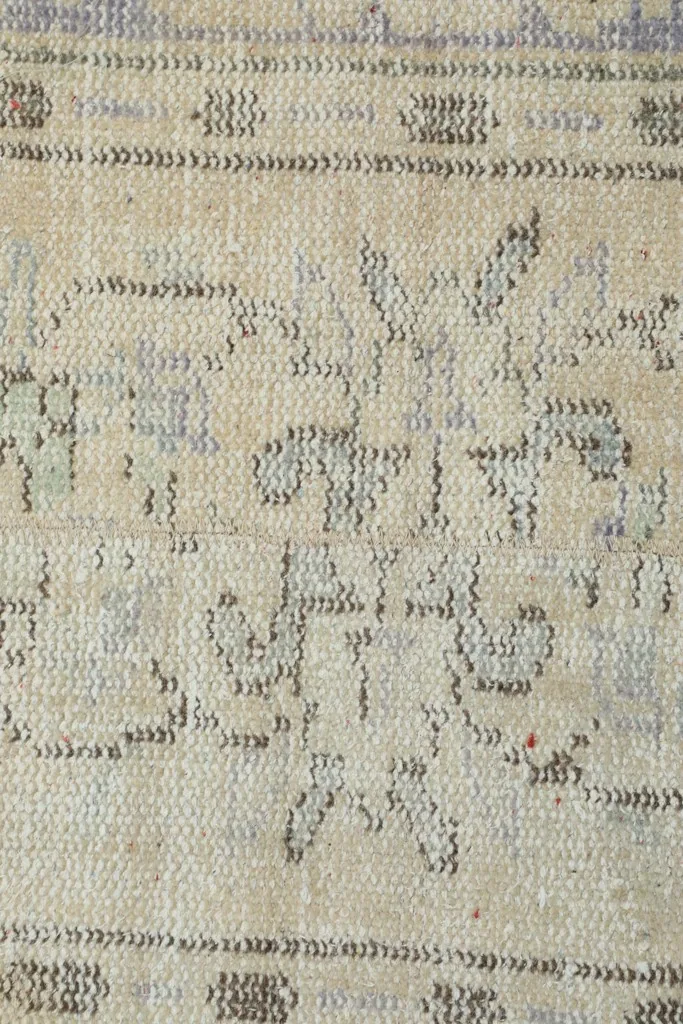 Detailed close-up of the hand-knotted wool pile and faded tribal motifs.