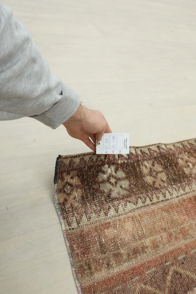Hand holding a card next to the rug to indicate scale and pile height