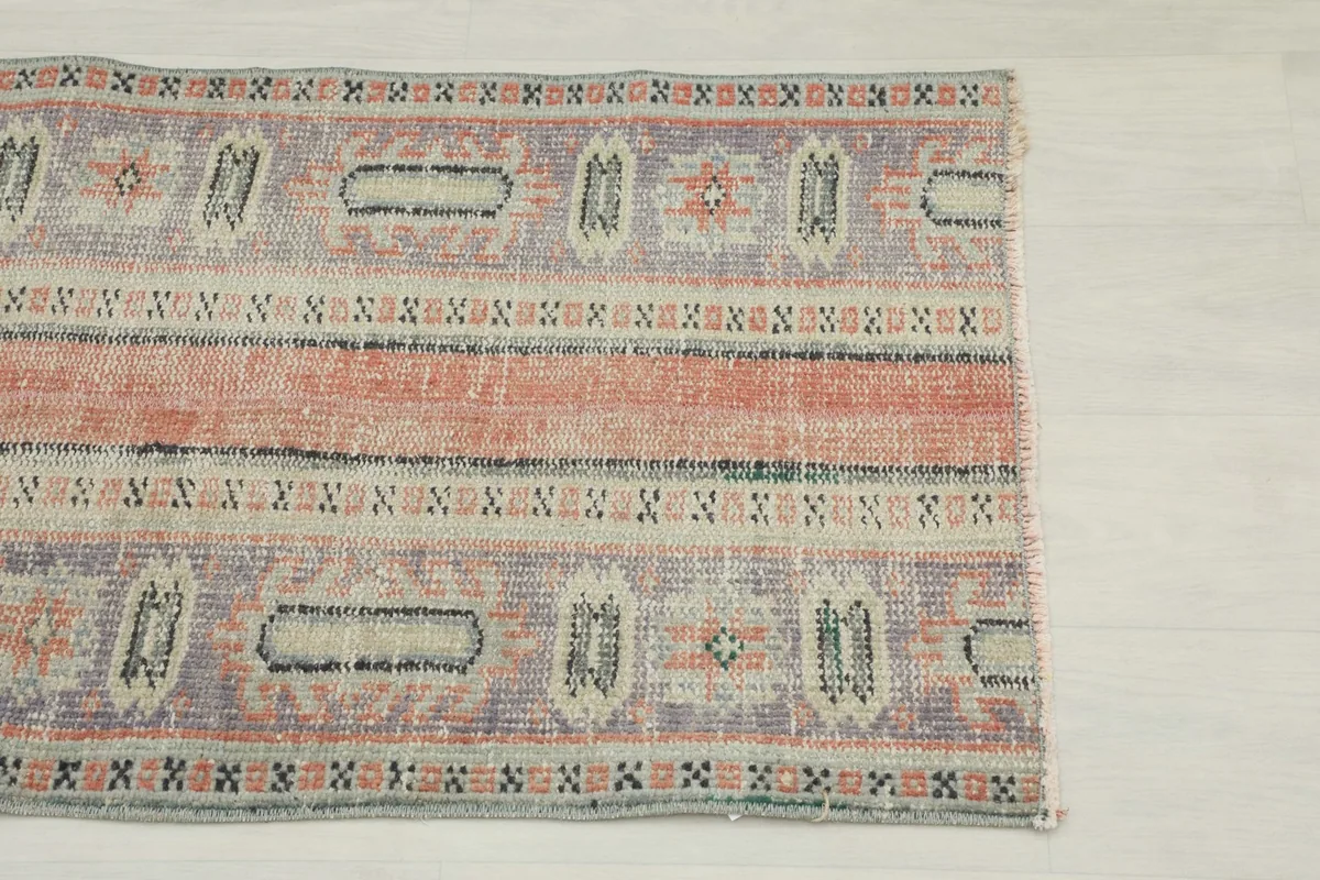 Close-up of the rug's top half, showing the rust stripe and blue geometric motifs
