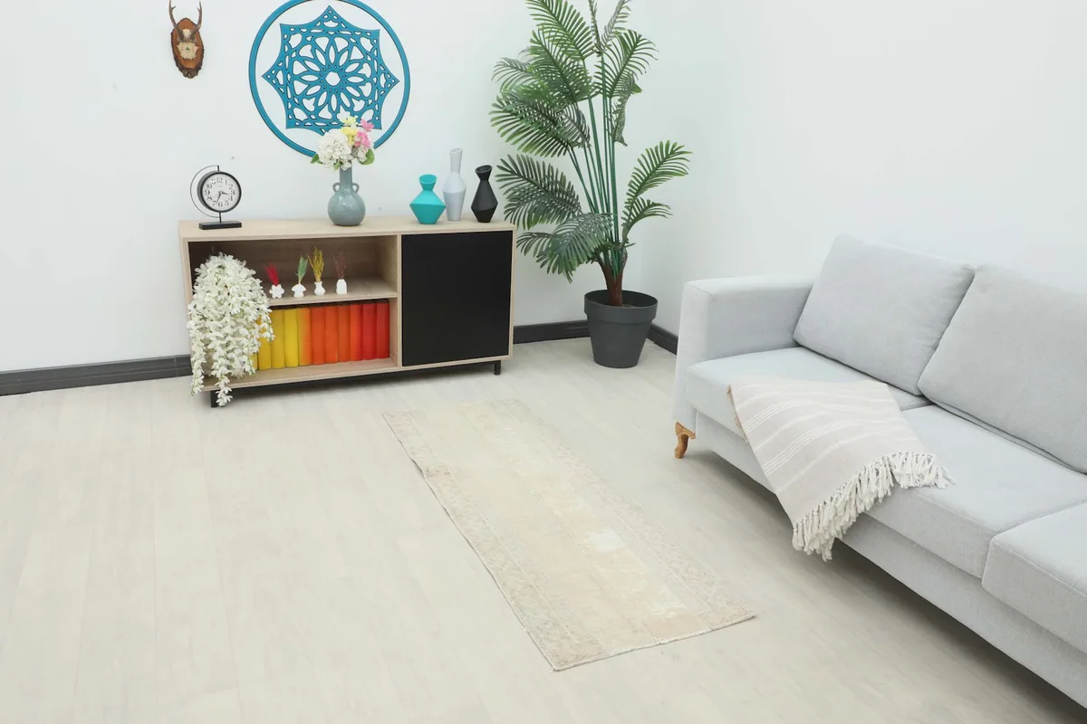 Runner rug placed in a living room setting next to a sofa and cabinet, showing its scale.