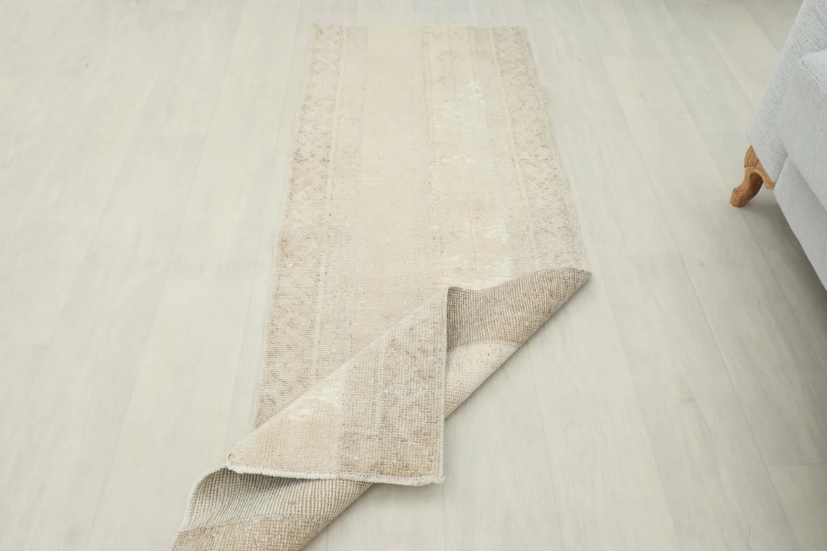 Runner rug with one corner folded back, displaying the pile and foundation.