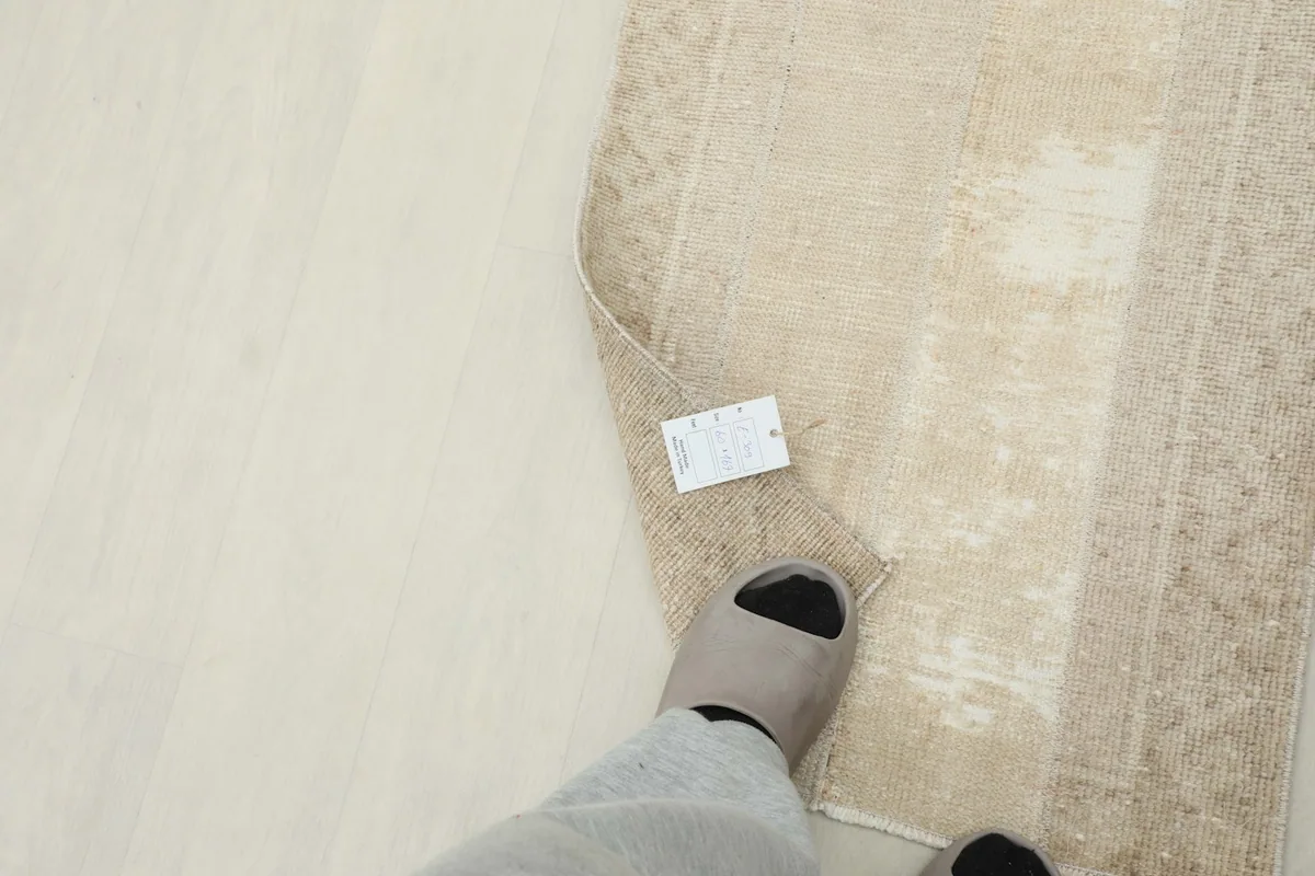 Foot in a slipper next to the rug, indicating scale and showing the texture from a personal perspective.