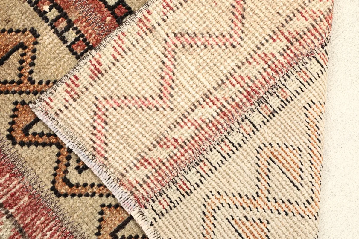 View of the back of the rug folded over, showing the cotton foundation and knotting