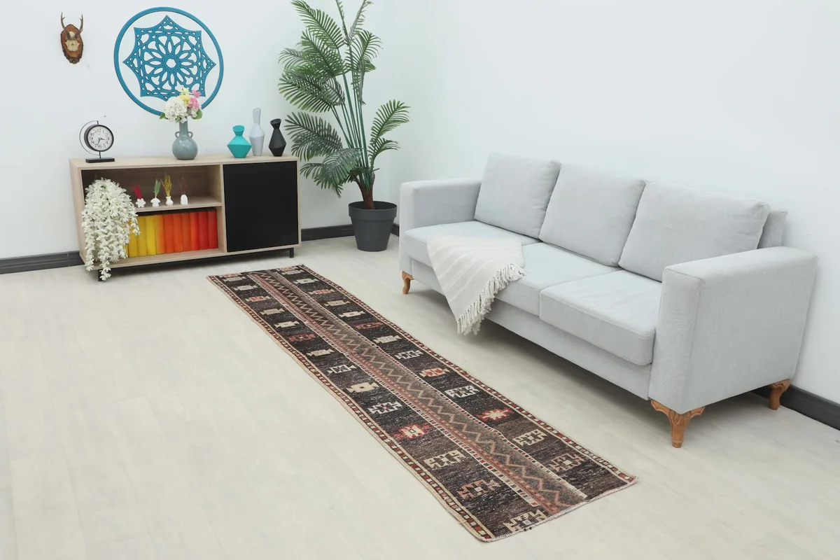 Long view of the brown geometric runner rug placed in a modern living room setting next to a sofa.