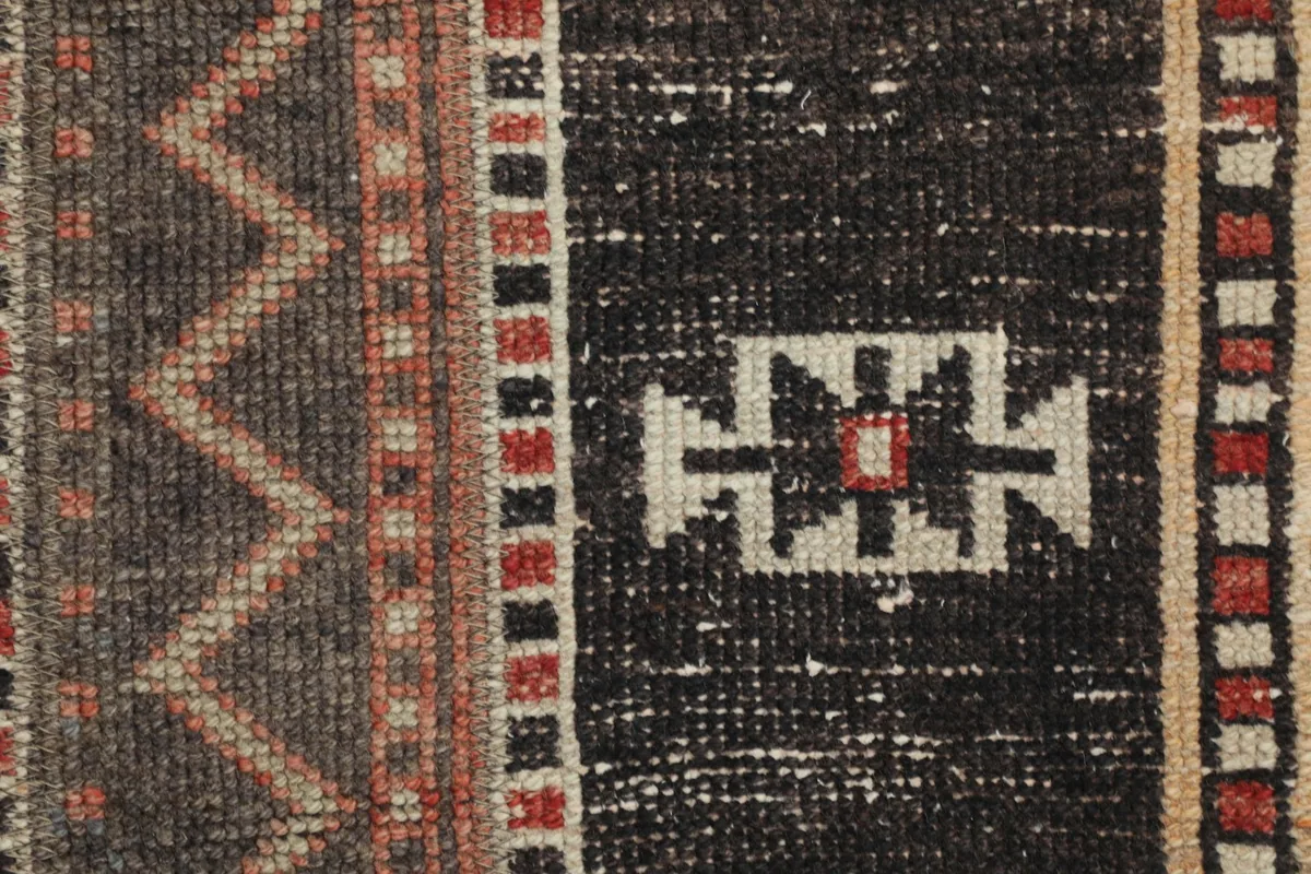 Close-up of the hand-knotted wool pile, showing individual geometric design elements and color variations.