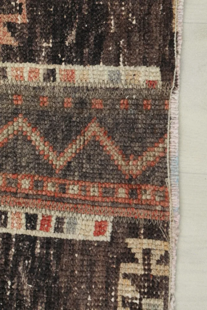 View of the low pile texture and the side binding of the vintage Anatolian runner rug.