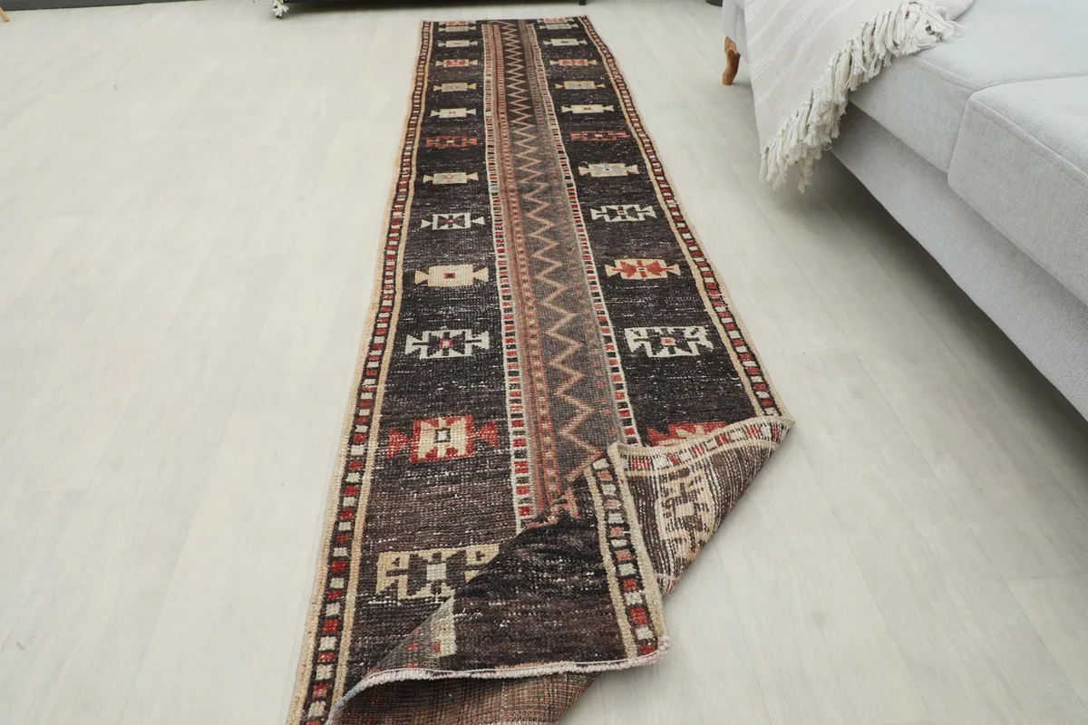 Long view of the runner rug with one end slightly folded, showing the full length and design.