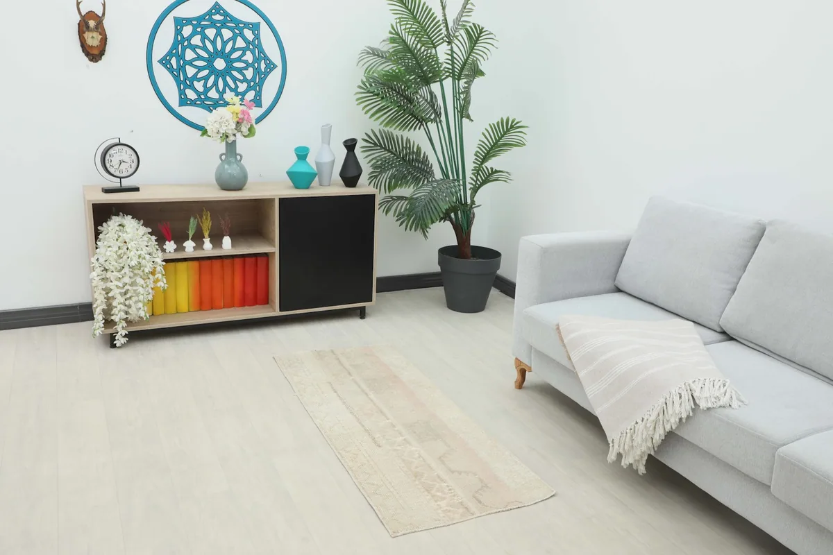Vintage beige and rose rug placed in a living room setting with a light gray sofa and wooden cabinet