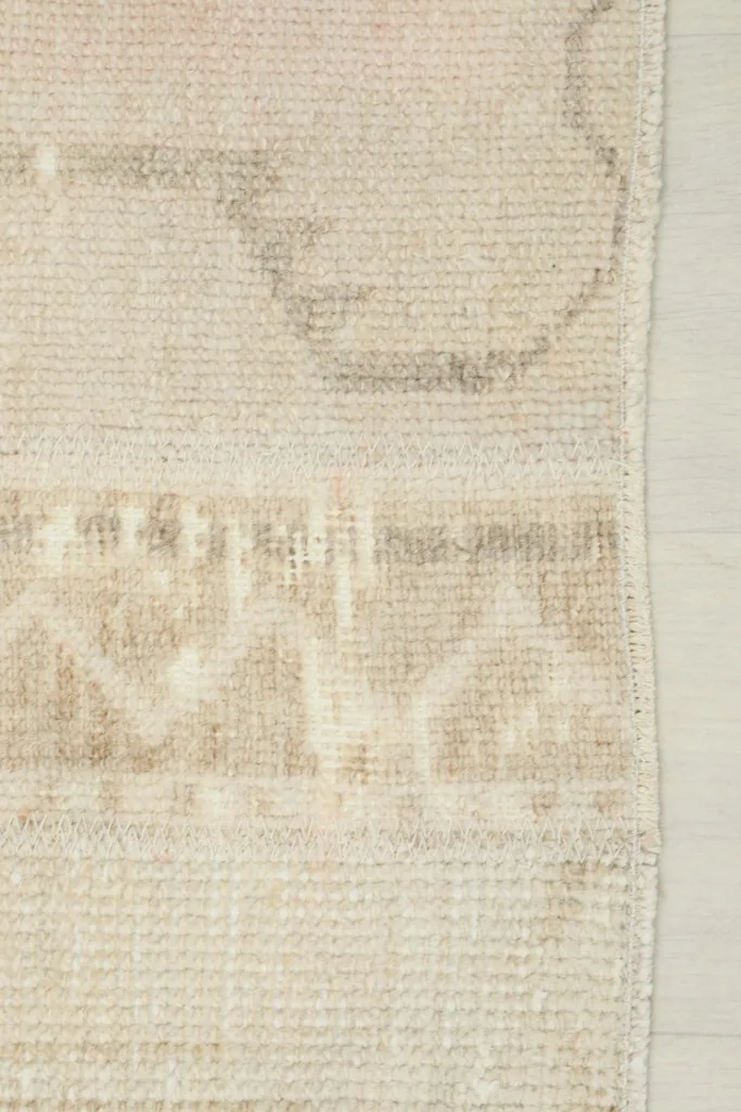 Detail of the subtle border and edge finishing of the beige and rose vintage rug