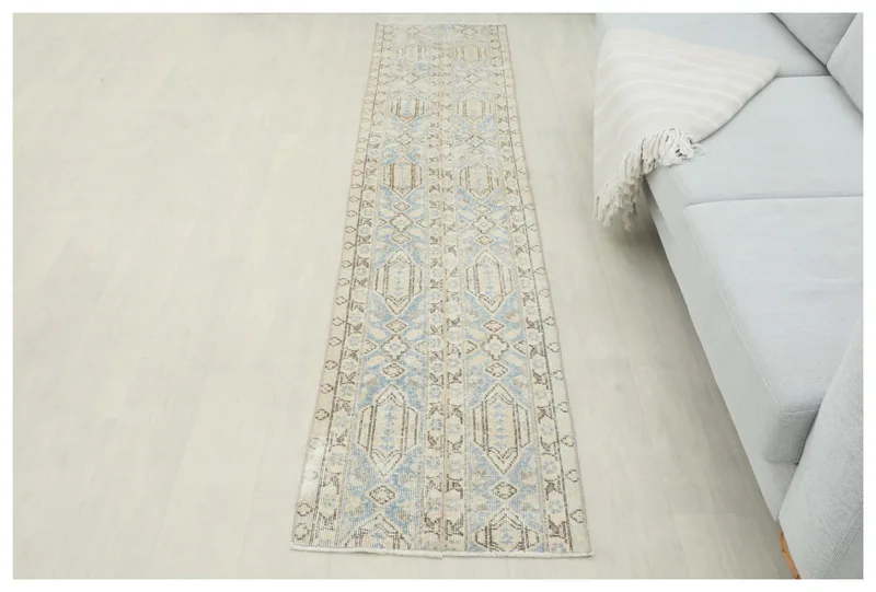 Full overhead view of the blue and beige geometric Anatolian runner on a white floor.