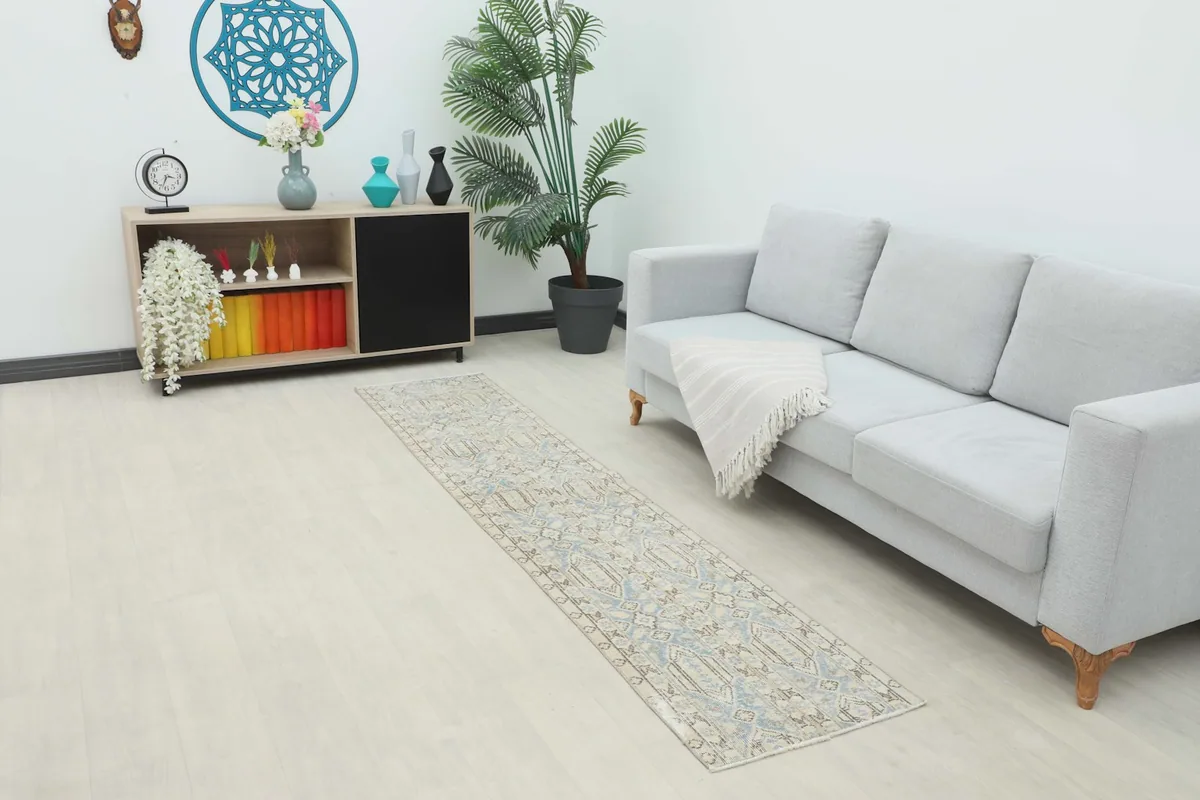 Vintage blue and beige runner rug extending from a light gray sofa in a living space.
