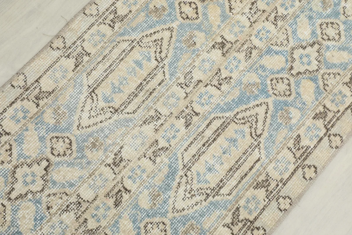Detailed view of the hand-knotted wool pile showing the blue and beige geometric motifs.