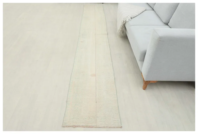 Full overhead view of the cream distressed Anatolian runner rug on a white floor.