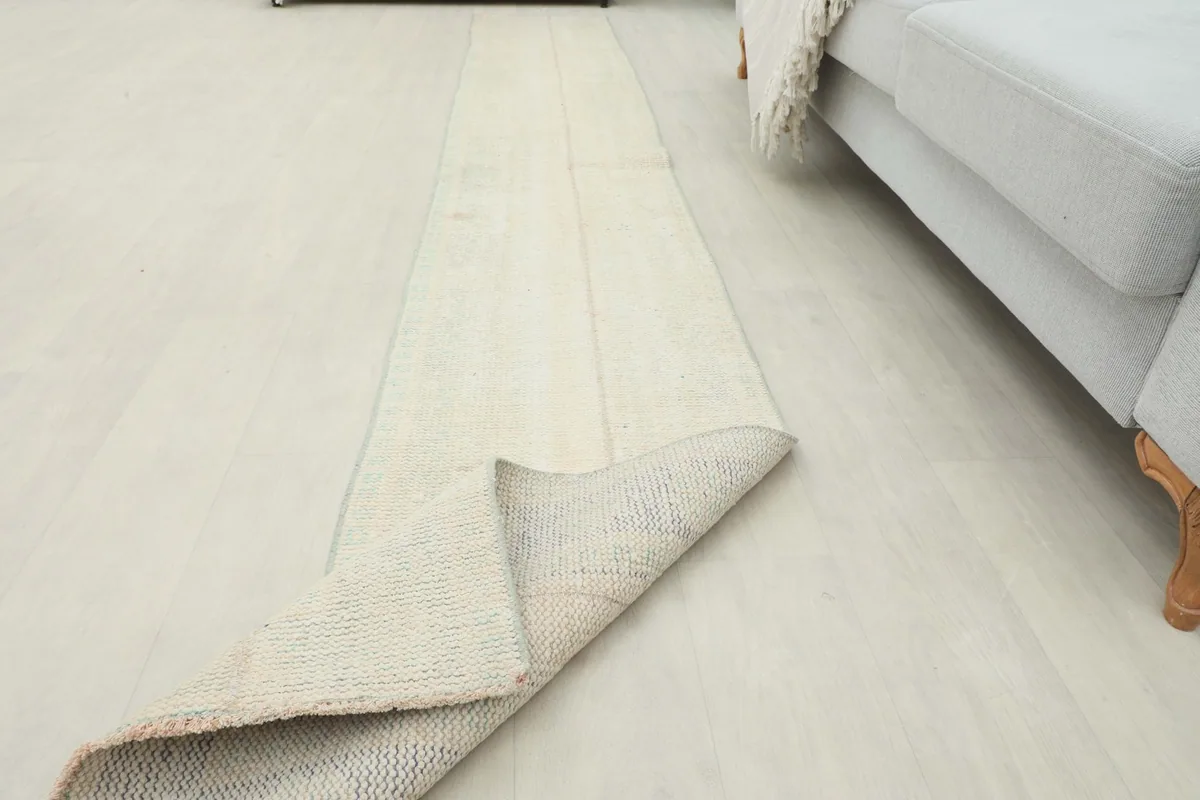 Runner rug partially unrolled in a room, illustrating its length and placement.