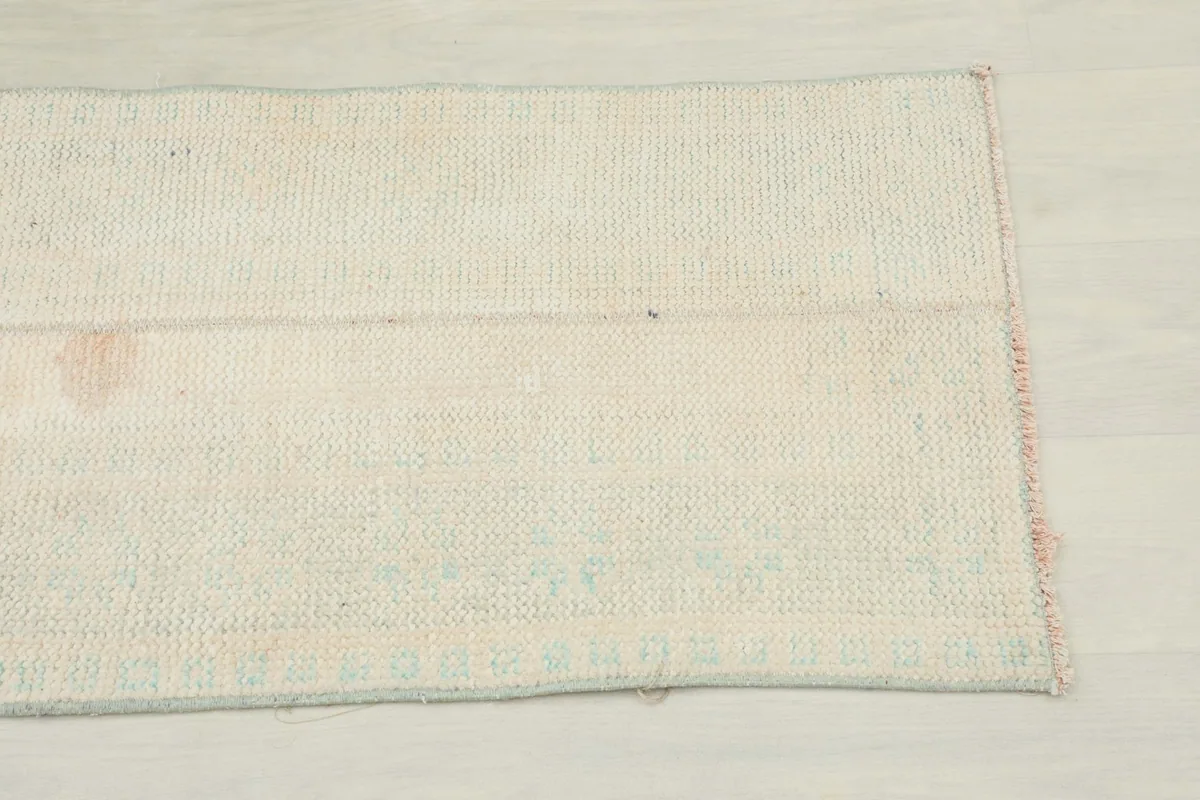 Close-up of one end of the cream runner rug, showing the distressed pile and subtle colors.