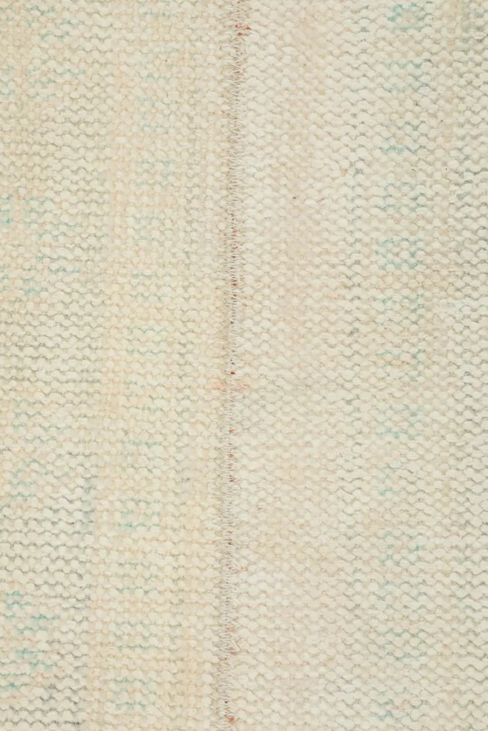 Very close view of the low wool pile, showing the hand-knotted texture and faint blue patterns.