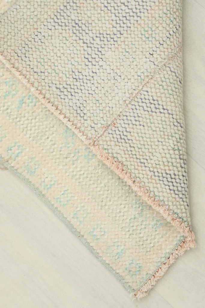 Corner of the rug folded to show both the pile and the reverse side, with fringe detail.