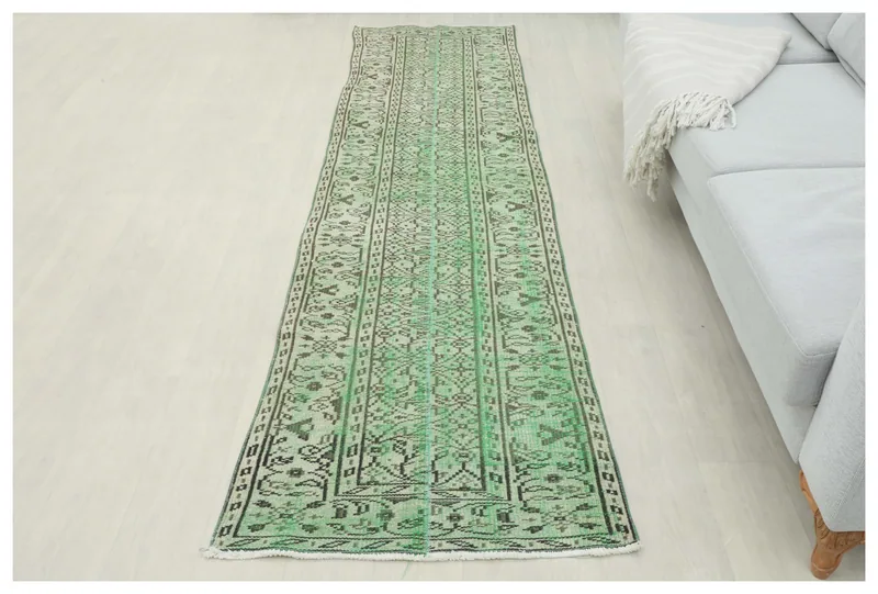 Full top view of the green geometric tribal runner rug on a white floor