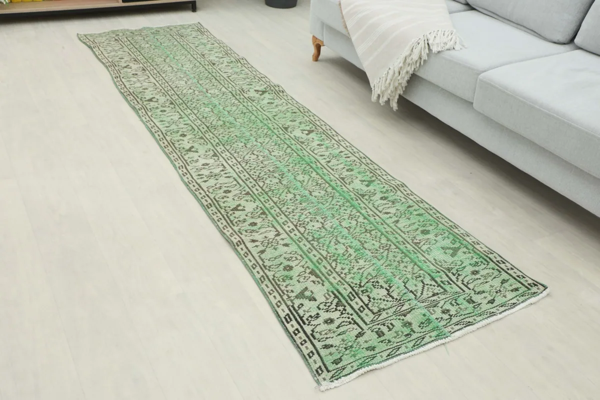 Angled view of the green vintage runner rug, showing its full length and pattern