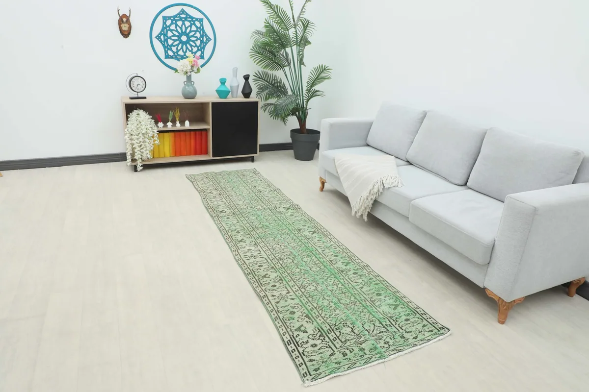 Green runner rug in a modern living room setting next to a sofa and console table