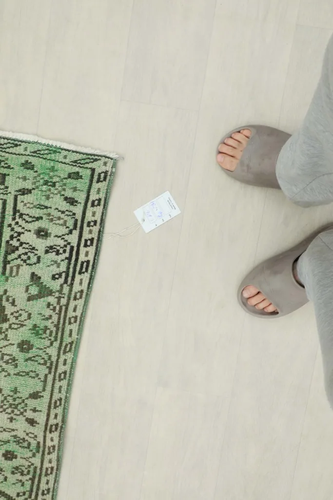 Overhead view of a corner of the rug next to feet for scale