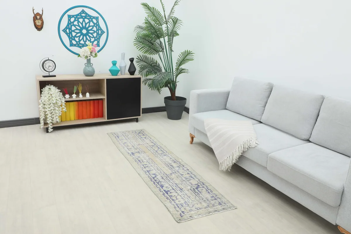 Vintage beige and blue runner rug placed in a modern living room setting with a light gray sofa.