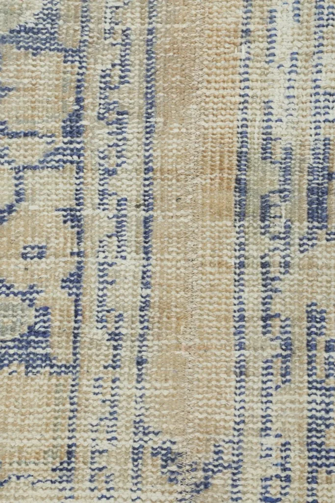 Extreme close-up of the rug's surface, highlighting the hand-knotted texture and worn patterns.