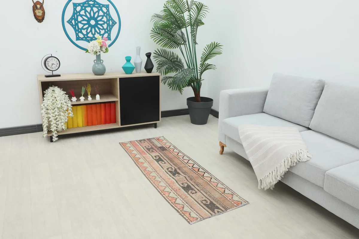 Vintage Anatolian runner rug placed in a living room setting, showing its scale and color next to a sofa.