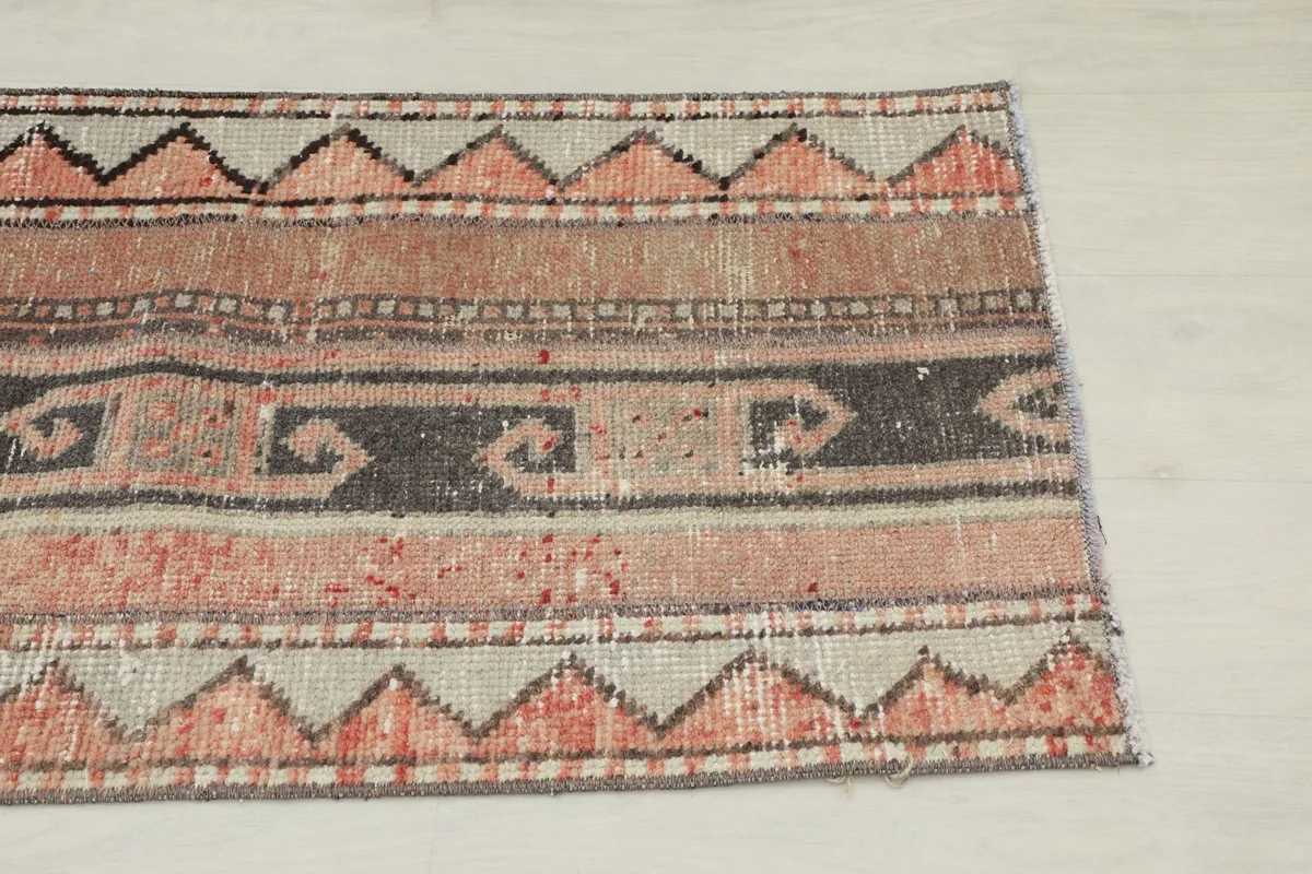 Close-up detail of the rug's patterns, showing rust, black, and beige zigzag and striped motifs.