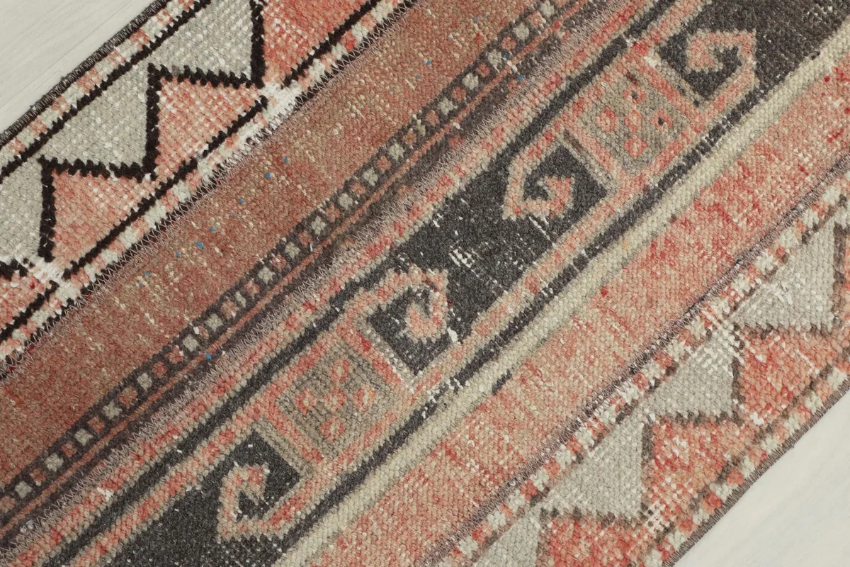 Detailed view of the rug's surface, focusing on the stylized S-shape motifs and color variations.